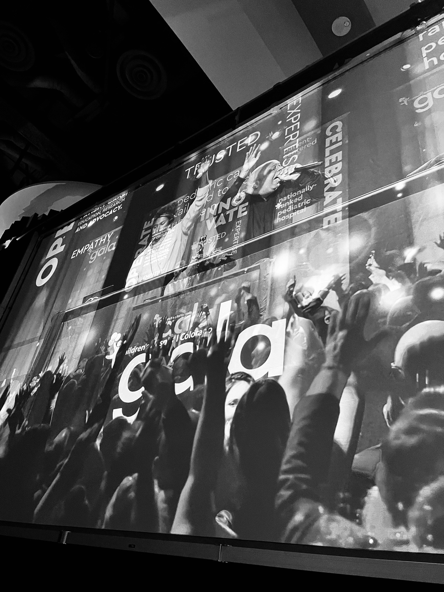 Black and white: the gala's big screen filled with the crowd, hands in the air, the event in full swing.