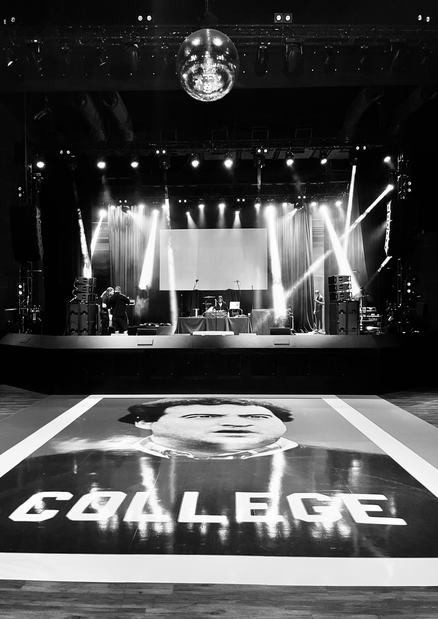Black and white: an empty venue before doors, stage lights up and a custom printed dance floor waiting.