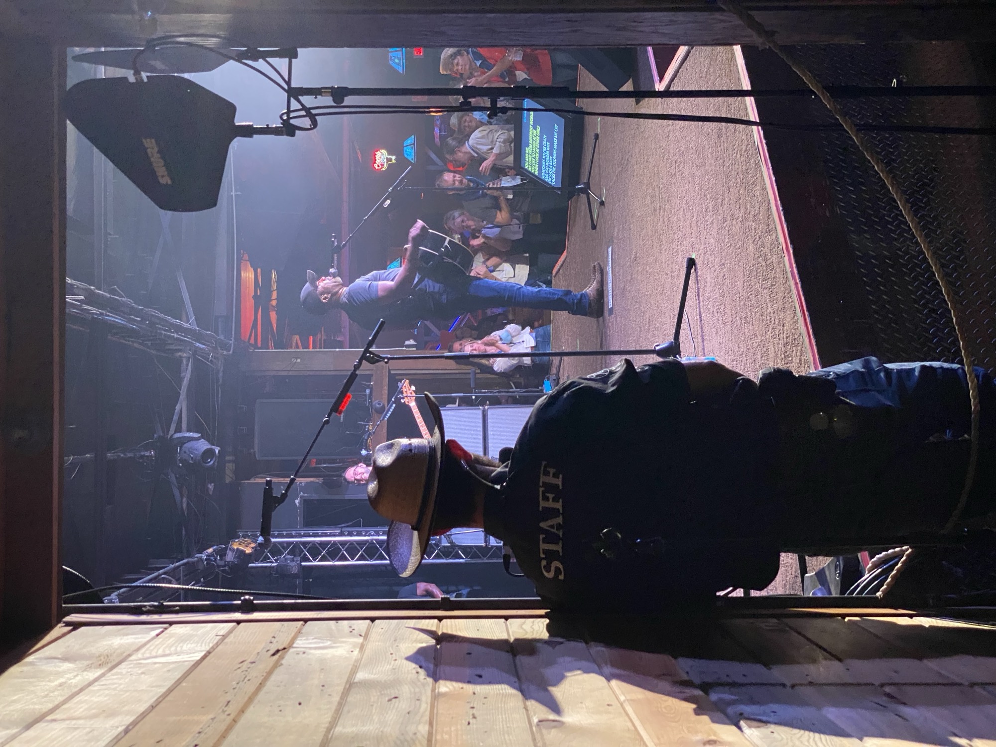 View from the wings: a security staffer in silhouette watching the artist perform to a full room.